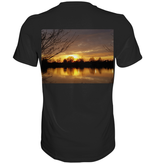 Das Abendspaziergang - Classic Shirt von Silbers Magic Shop aus ringgesponnener Baumwolle bietet außergewöhnlichen Komfort. Auf der Rückseite ist ein lebendiges Sonnenuntergangsbild mit Wasserreflexionen und Baumsilhouetten für eine ruhige und malerische Aussicht zu sehen.