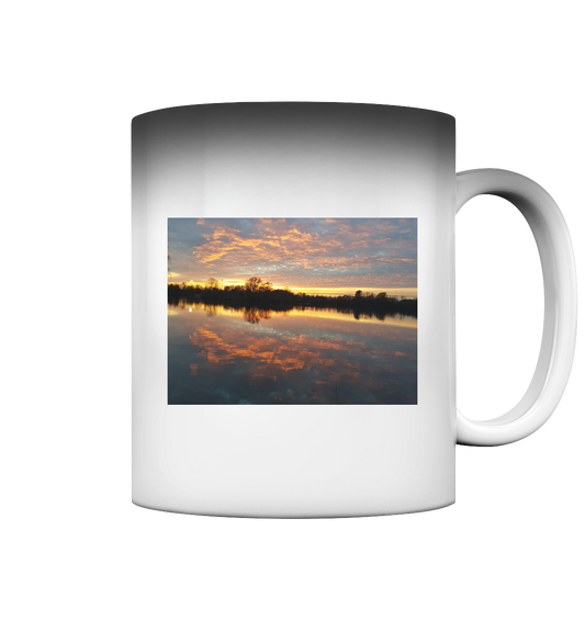 Der See am Abend - Magic Mug von Silbers Zauberladen zeigt einen malerischen Sonnenuntergang über einem ruhigen See, mit Bäumen, die sich vor einem lebendigen Himmel abheben. Die leuchtenden Orange-, Rosa- und Blautöne spiegeln sich im Wasser und bilden einen ruhigen Spiegeleffekt, der durch den Magic-Thermo-Effekt sichtbar wird.