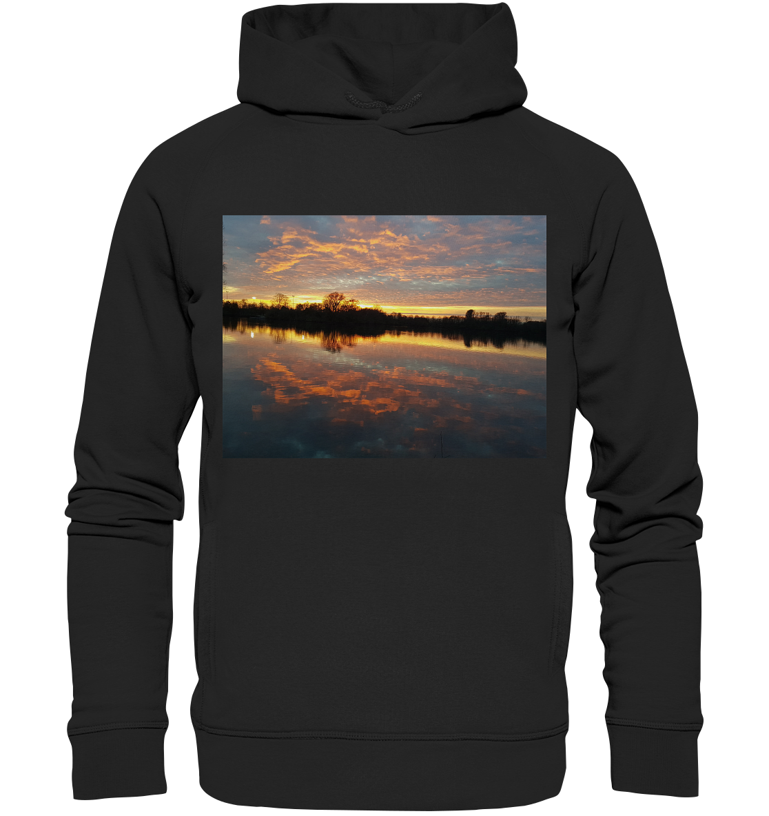 Eine Person trägt einen See am Abend - Organic Fashion Hoodie von Silbers Magic Shop, der eine lebhafte Sonnenuntergangsszene zeigt. Das Bild auf dem Hoodie zeigt einen ruhigen See, der den farbenfrohen Himmel mit orangefarbenen, rosafarbenen und violetten Farbtönen reflektiert, und im Hintergrund sind Baumsilhouetten zu sehen. Hergestellt aus recyceltem Polyester für einen umweltfreundlichen Touch.