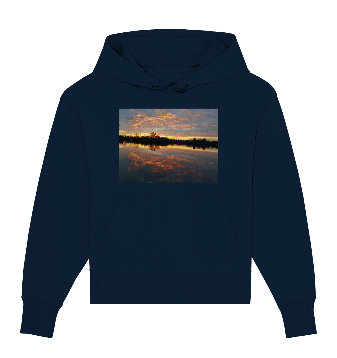 Wir präsentieren den See am Abend - Organic Oversize Hoodie von Silbers Magic Shop, einen dunkelblauen Hoodie mit einem rechteckigen Bild auf der Brust. Das Bild zeigt einen ruhigen Sonnenuntergang über einem ruhigen See mit Bäumen, die sich gegen den farbenfrohen Himmel abheben, und leuchtend orangefarbenen und rosa Wolken, die sich perfekt im Wasser spiegeln. Hergestellt aus Bio-Baumwolle für mehr Nachhaltigkeit.