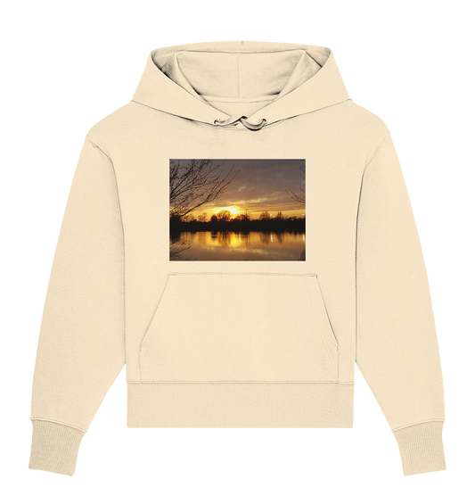 Wir präsentieren den „Abendspaziergang – Organic Oversize Hoodie“ von Silbers Magic Shop. Dieser beigefarbene Unisex-Hoodie verfügt über eine große Vordertasche und zeigt auf der Vorderseite einen ruhigen Sonnenuntergang am Seeufer mit Baumsilhouetten, die sich im ruhigen Wasser spiegeln. Hergestellt aus nachhaltiger Bio-Baumwolle ist er eine umweltfreundliche Wahl, die sowohl Stil als auch Nachhaltigkeit bietet.