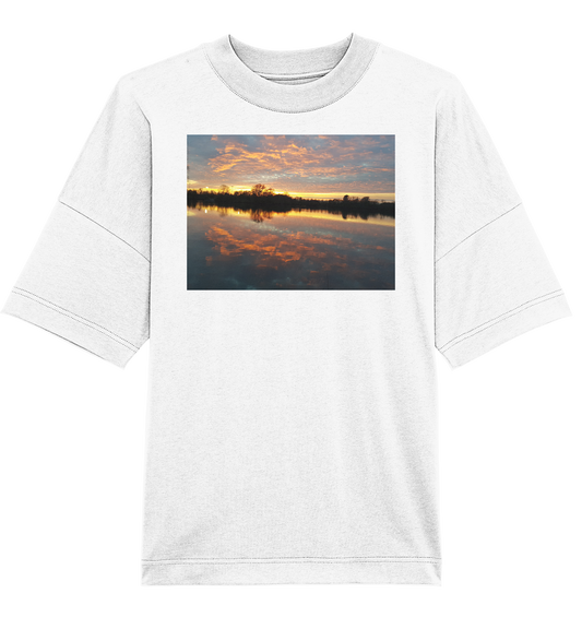 Das See am Abend - Organic Oversize Shirt von Silbers Magic Shop zeigt einen ruhigen Sonnenuntergang am Seeufer in leuchtenden Orange-, Rosa- und Blautönen mit Wolken, die sich im ruhigen Wasser spiegeln. Es besteht aus Bio-Baumwolle und bietet sowohl Komfort als auch Nachhaltigkeit.