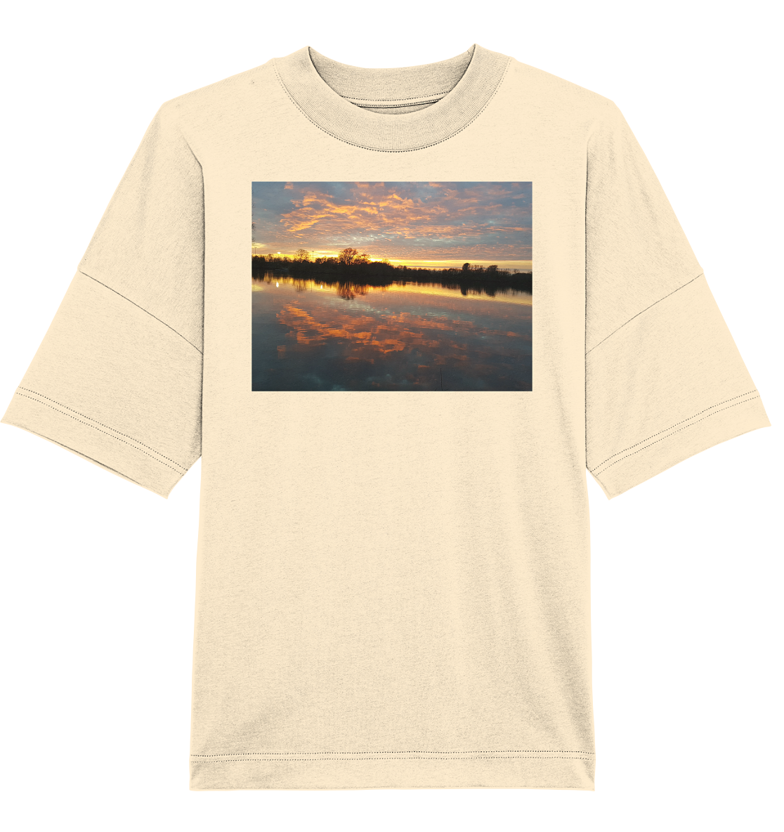 Das „See am Abend“ Bio-Oversize-Shirt von Silbers Magic Shop ist ein beiges Shirt, das mit einem rechteckigen Bild eines ruhigen Sees bei Sonnenuntergang verziert ist. Der Himmel zeigt leuchtend orange und rosa Wolken, die sich wunderschön im glatten Wasser spiegeln, mit Baumsilhouetten im Hintergrund.